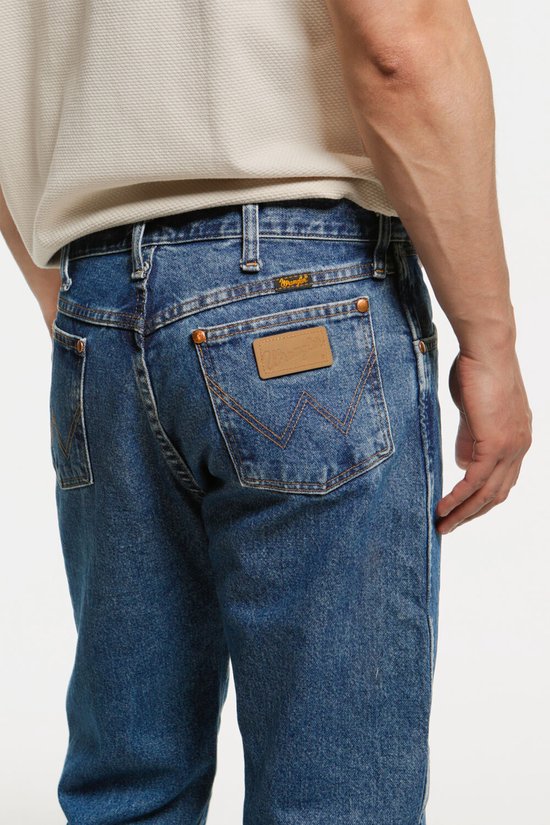 Achterkant van een blauwe jeans met een bruine lederen patch met logo.