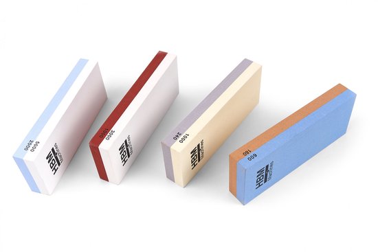 Vier dubbelzijdige wetstenen met grofheden 240-1000, 1000-3000, 2000-5000. Kleuren wit/blauw, crème/rood, beige/grijs en blauw/bruin.