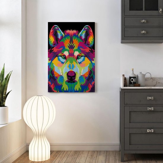 Abstracte wolvenkop in veelkleurige geometrische stijl, hangend aan een witte muur naast een donkere kast met lades.