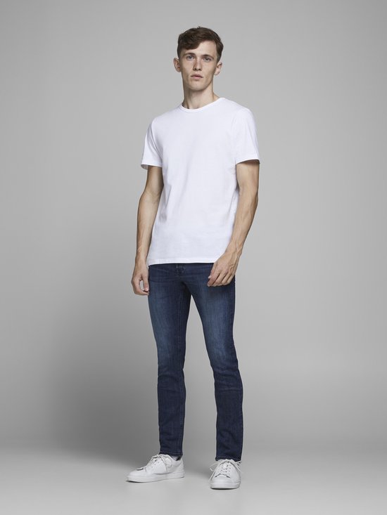 Model in een witte T-shirt en een donkerblauwe Jack & Jones slim fit jeans.