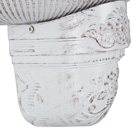 Close-up van de onderkant van een witte muurfontein met sierlijke, verweerde details.