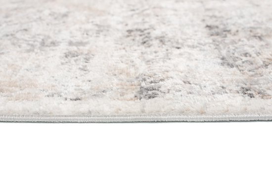 Gros plan du bord d'un tapis gris clair avec coutures détaillées et texture douce.