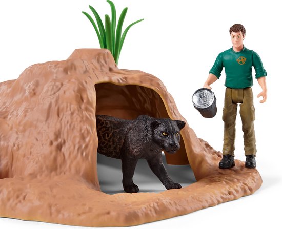 Zwarte speelgoed panter die uit een bruine grot komt, naast een mannelijke verzorger met een lamp.