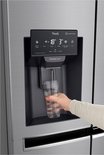 Hand vult een glas met water uit de dispenser van een LG Amerikaanse koelkast.