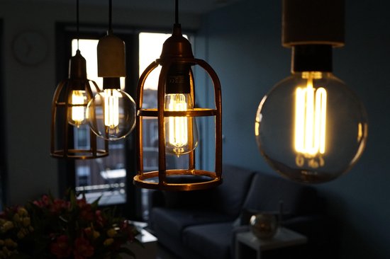 Drie hanglampen met zichtbare gloeilampen, één met een koperkleurig metalen frame.