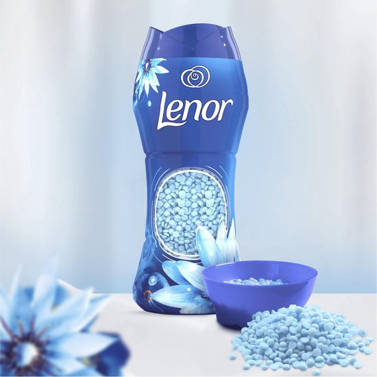 Bouteille de perles de parfum Lenor "Zeebries" à côté d'un bol bleu rempli de perles et d'une pile de vêtements pliés.