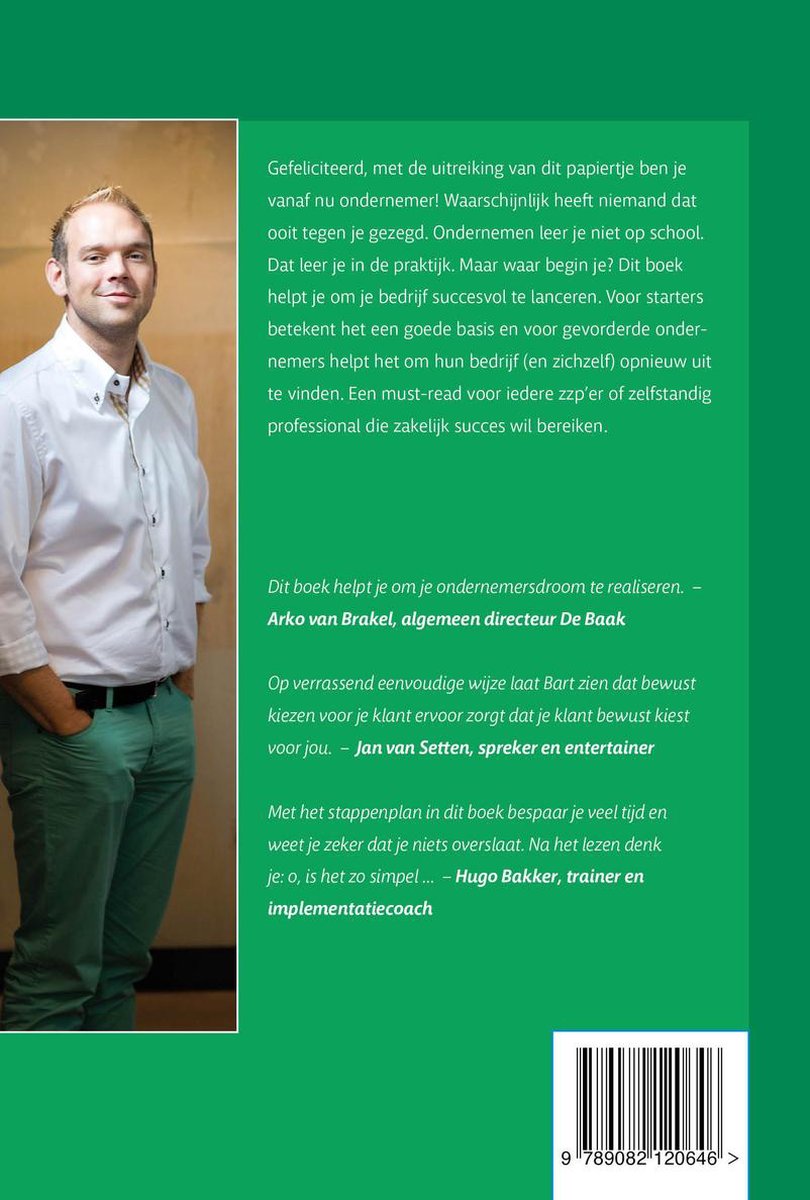 Man in wit overhemd en groene broek staat met handen in zakken.
