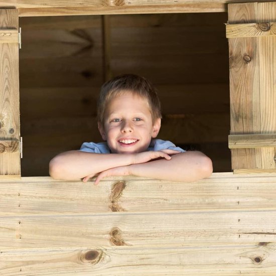 Jongetje met blond haar, lachend, leunt op een houten speelhuisje.