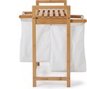 Vooraanzicht van een bamboe wasmand met twee witte waszakken en een plank.