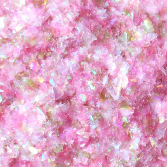 Close-up van roze eetbare glitters in vlokvorm met iriserende effecten.