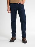 Model draagt een beige polo en donkerblauwe straight fit jeans.