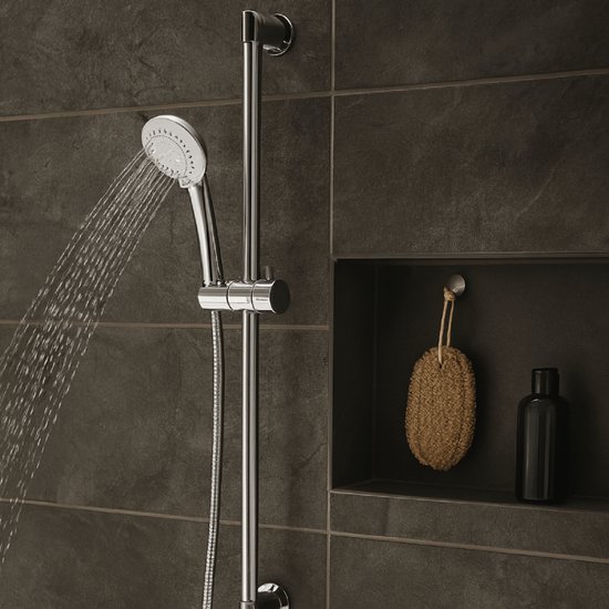 Zilverkleurige handdouche met verstelbare stang, water spuitend, tegen donkergrijze tegels.