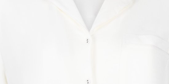 Detailopname van de knopen en kraag van een wit pyjamashirt.