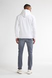 Man van achteren gezien, draagt een witte hoodie en grijze slim fit jeans met naden op de achterzakken.