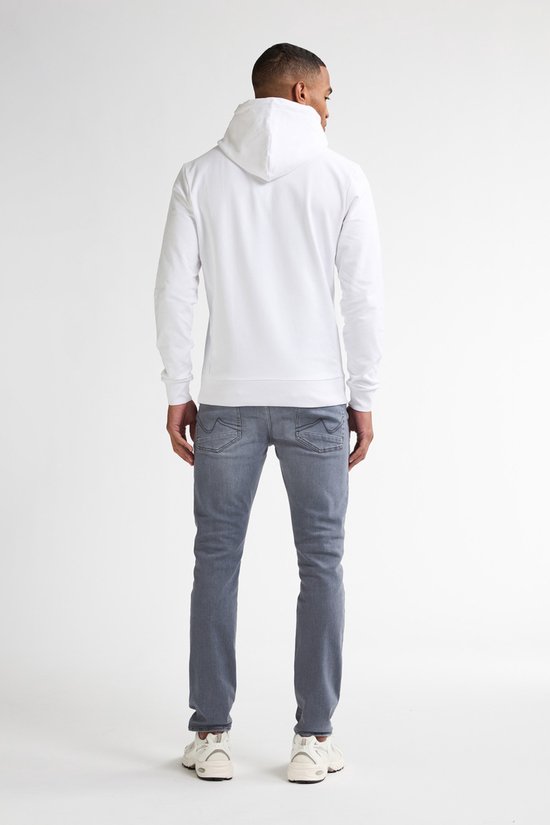 Man van achteren gezien, draagt een witte hoodie en grijze slim fit jeans met naden op de achterzakken.