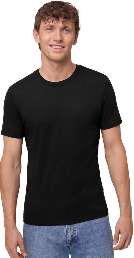 Jeune homme en jean bleu et T-shirt noir, souriant à la caméra.