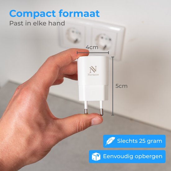 Hand houdt een compacte witte Nuvance USB-oplader (4x5cm, 25 gram) vast bij een stopcontact.