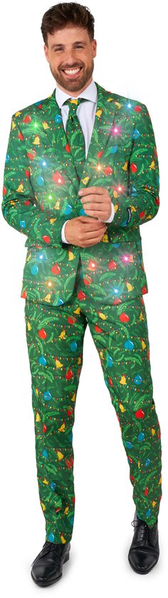 Man in groen Suitmeister kerstpak met dennentakken, kerstballen en bellen. Het pak heeft ingebouwde lichtjes.