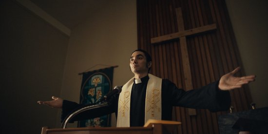 Priester staat achter een lessenaar in een kerk.