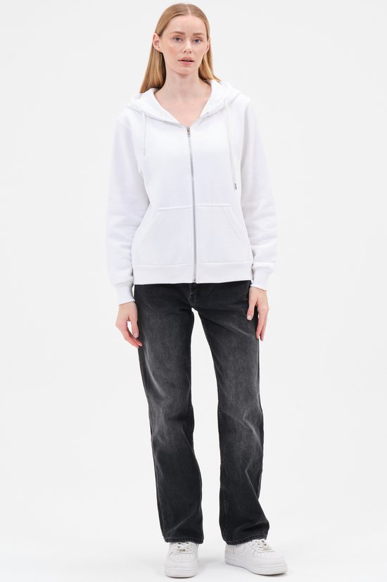 Model staat met witte hoodie met rits en capuchon en grijze jeans.