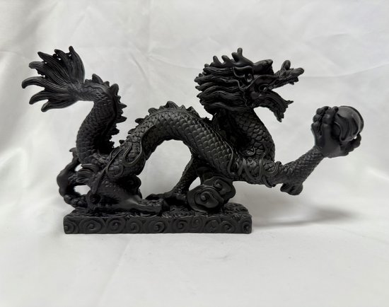 Zwart Feng Shui draakbeeld met een bal, details op de basis.