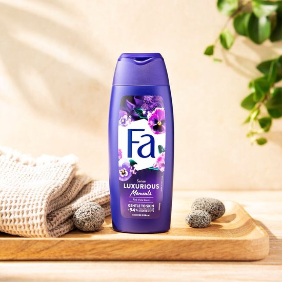 Fa Luxurious Moments douchecrème met roze viooltjes, naast een opgerolde handdoek en stenen.
