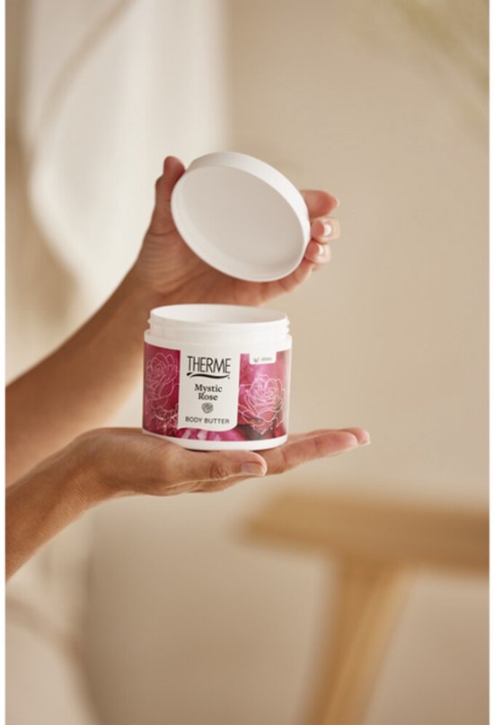 Handen houden een pot Therme Mystic Rose body butter en de open deksel vast.