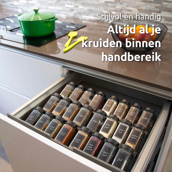 Een open keukenlade met een zwart kruidenrek vol met kruidenpotjes, netjes geordend.