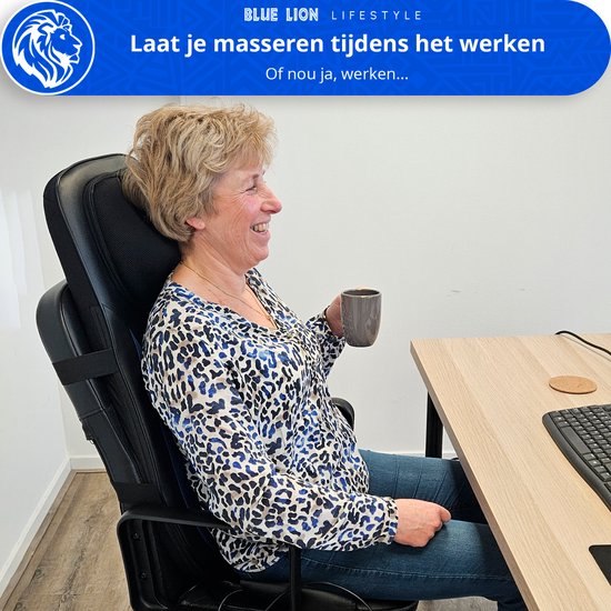 Vrouw met blonde haren zit op een bureaustoel, drinkt koffie en lacht, terwijl ze het massagekussen gebruikt.