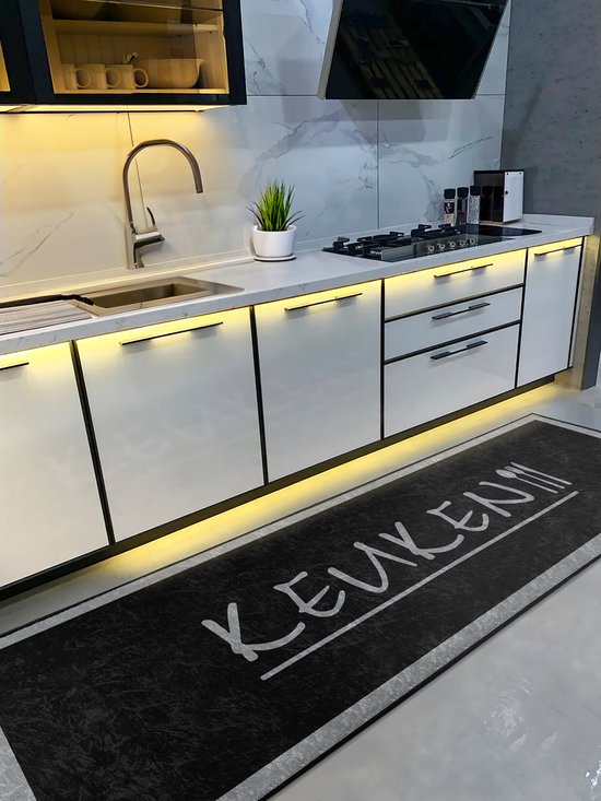 Un tapis de cuisine avec le texte "KEUKEN" est placé devant une cuisine blanche moderne avec un plan de travail.
