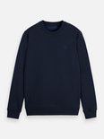 Donkerblauwe sweater met ronde hals. Het geborduurde vierkante logo op de borst is zichtbaar.