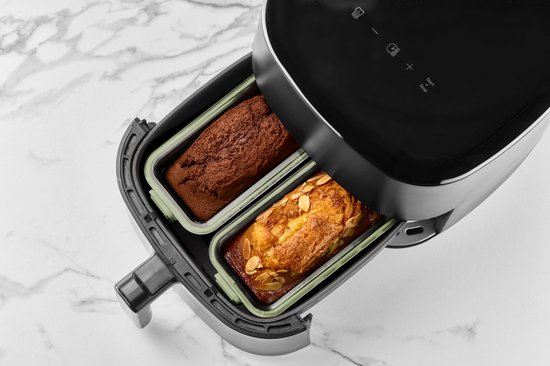 Twee lichtgroene glazen airfryer schalen, één met chocoladecake, de ander met citroencake, geplaatst in een zwarte airfryer.