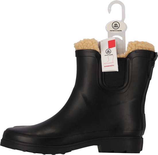 Zwarte Chelsea regenlaars met crèmekleurige fake fur voering, hangend aan een kledinghanger met labels.