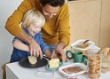 Een man en jongen maken brood klaar met een botervloot.