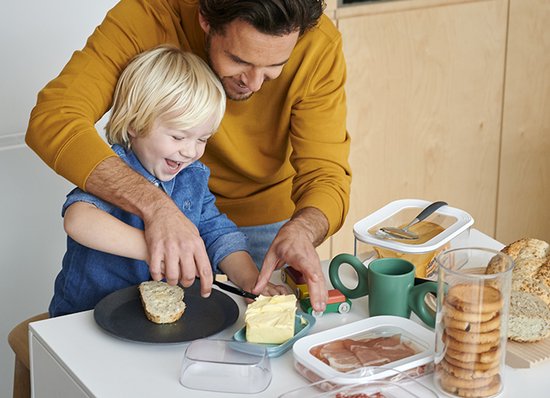 Een man en jongen maken brood klaar met een botervloot.