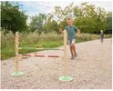 Jongen rent naar een hordenparcours met twee staanders en twee balken: groen-hout en rood-wit geblokt.