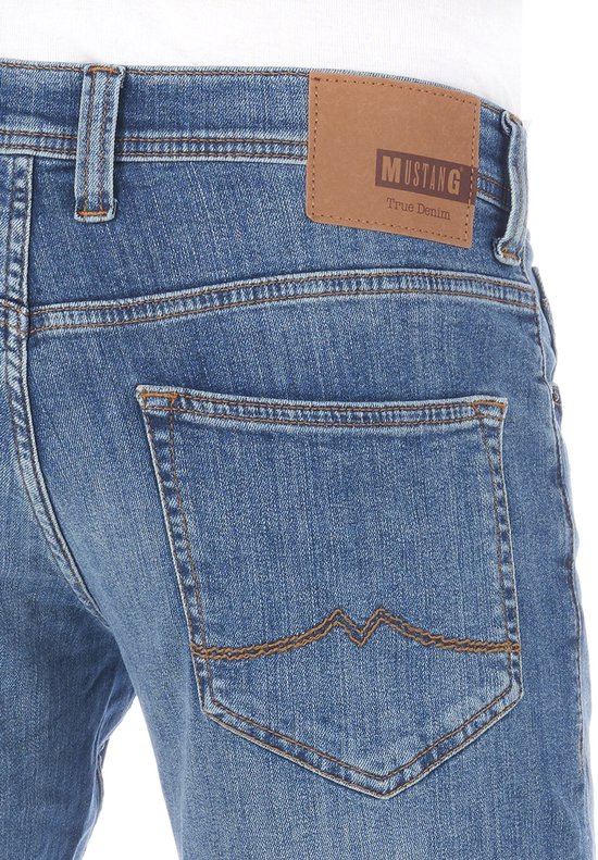 Detailopname van de achterzak van een blauwe Mustang jeans met het opschrift Mustang True Denim op een leren label.