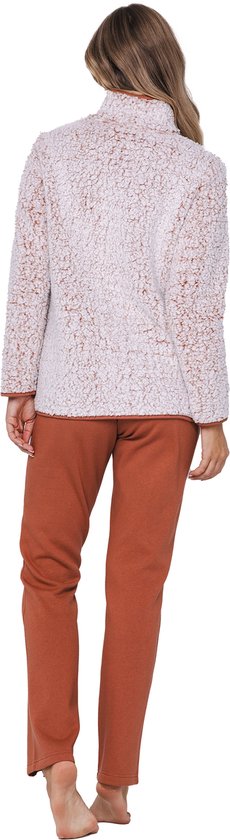 Vrouw draagt een lichtroze teddy fleece trui met bruine accenten en een bruine broek.