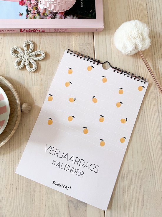 Een verjaardagskalender met een papagen print, liggend op een houten tafel.