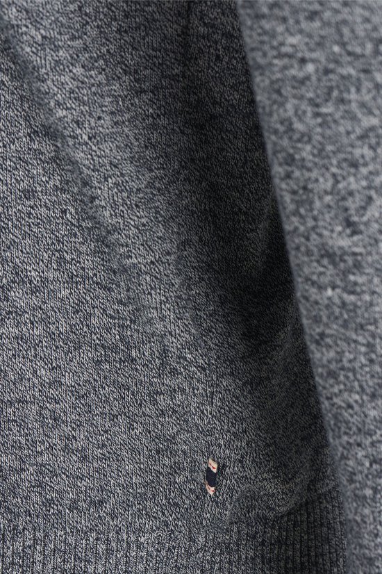 Gedetailleerd beeld van een grijze gebreide trui met een klein logo op de heup.