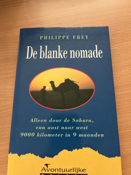 Boek 'De blanke nomade' door Philippe Frey. Een silhouet van een kameel en ruiter bij zonsondergang in de woestijn.