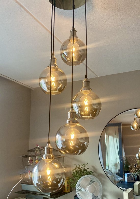 Vijf hanglampen met rookglazen bollen en zichtbare gloeidraden, hangend aan zwarte koorden aan een metalen plafondplaat.