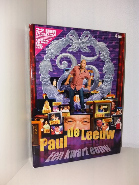 Dvd-box met Paul de Leeuw staand, omringd door televisies met beelden uit zijn carrière.