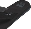 Close-up van een zwarte Reef slipper, focus op de band met Reef logo.