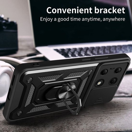 Zwarte telefoonhoes met ringhouder, camera-afdekking, op een houten tafel met laptop en koptelefoon.