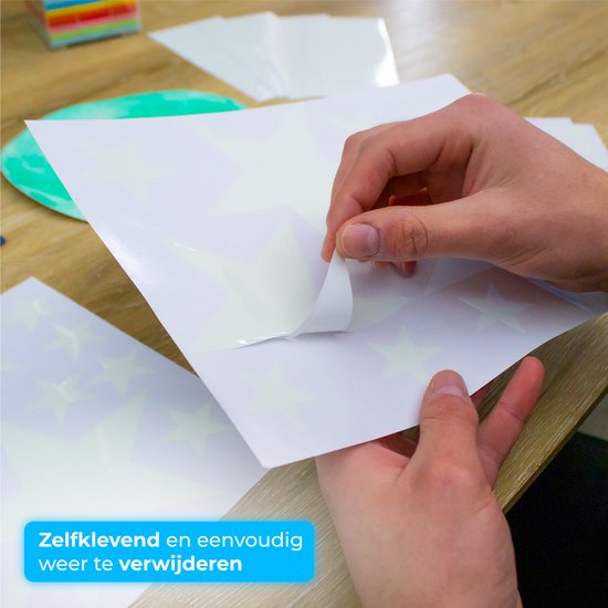 Handen pellen een grote glow-in-the-dark sterrensticker van een vel. De sticker is wit met lichtgevende sterren.