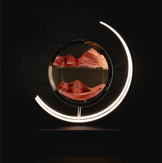 Rode en witte zandkunst in een rond glas met een halvemaanvormige zwarte lamp met verlichting.