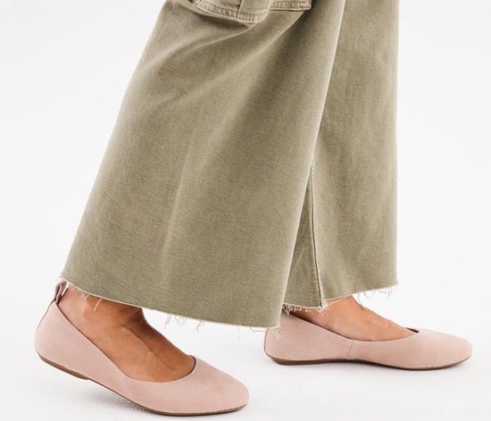 Pieds d'une femme portant des ballerines roses et un pantalon cargo vert.