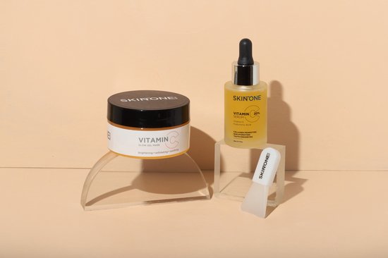 Gouden gelmasker, vitamine C serum en spatel op transparante displays.