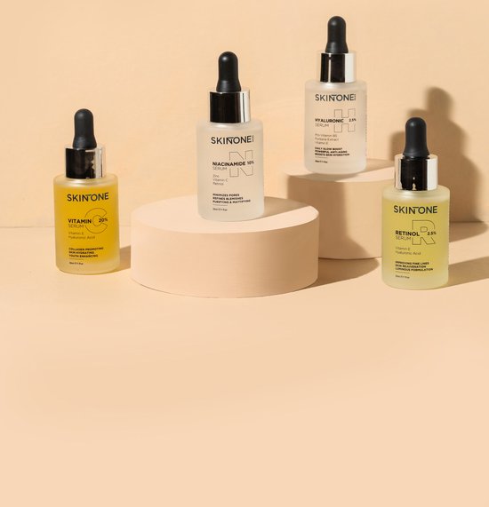 Vier SKINTONE SKIN serums op een podium: vitamine C, niacinamide, hyaluronzuur en retinol.